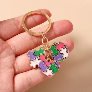 Dettaglio del portachiavi a cuore con puzzle colorato e anello in metallo dorato in mano