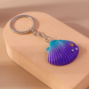 Macro detail of a gradient seashell keychain with gold star and silver orb accents