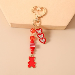 Dettaglio del portachiavi con perline rosse, cuori luccicanti, chiusura dorata e orsetto