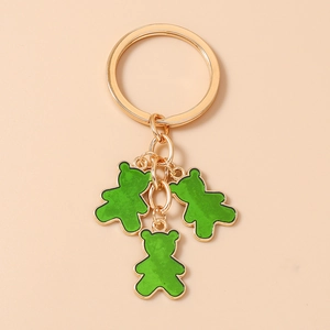 Detalle de los lindos ositos verdes colgantes en un anillo de llavero dorado