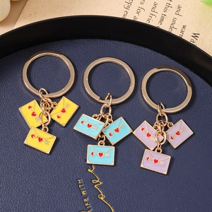 Detail of colorful enamel heart envelope keychains on a textured blue display tray