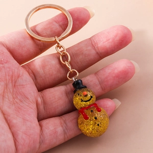 Macro shot of a yellow snowman keychain with glitter texture and gold keyring
