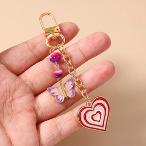 Detailed view of golden keychain with enamel butterfly, heart charms and colorful beads