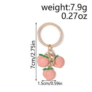 Close-up showing the size dimensions and gold-tone peach charms on a keychain