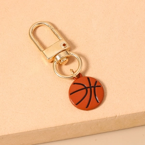 Detail of a basketball keychain with golden lobster clasp on a textured display stand