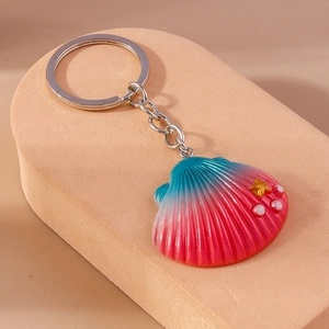 Detail of shell keychain with blue-red gradient, gold stars and white pearls on stand