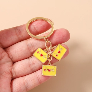 Detailed close-up of hand holding golden heart envelope charms on a sturdy keychain