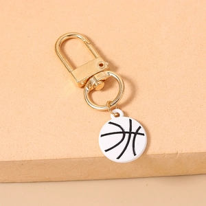 Detail of a white basketball keychain charm with golden metal lobster clasp and ring