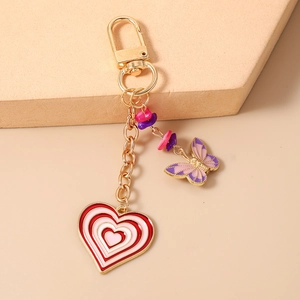 Close-up of heart and butterfly keychain charms with pink stones and golden finish