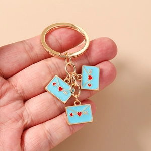 Detail of gold metal keychain with three light blue envelopes and red heart charms