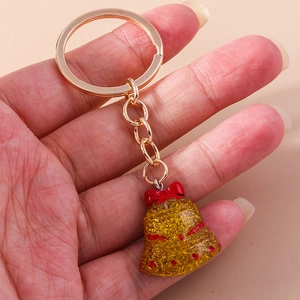 Handheld view of Christmas bell keychain with red bow and glittery gold finish