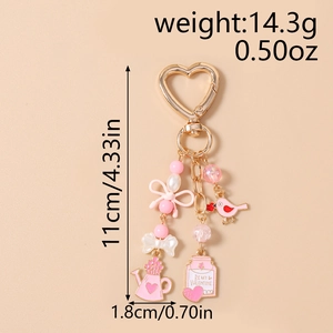Detail view of pink enamel bird and love letter charms on a golden beaded keychain