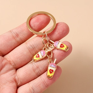 Detail of hand holding gold enamel bubble tea keychains with small heart patterns