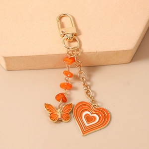 Detail of orange butterfly and heart charms on a golden metal keychain link