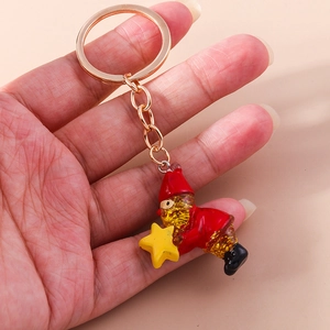 Close-up of a Christmas gnome keychain with gold glitter beard held in hand