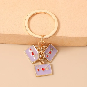 Detailed view of purple envelope charms with red hearts on a gold keychain ring