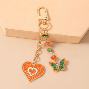 Detailed view of gold keychain with orange enamel heart and butterfly charms