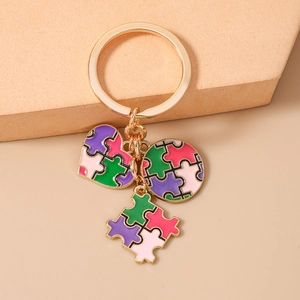 Dettaglio portachiavi dorato con ciondoli a puzzle colorati a forma di cuore