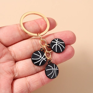 Détail d'un porte-clés doré orné de trois breloques de basket-ball noires texturées