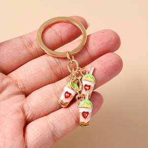 Detailed macro view of gold-tone keychain with three colorful milk tea charms in hand