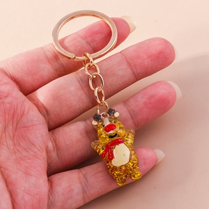 Close-up of glitter reindeer keychain with red scarf held by hand in soft light