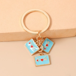 Detailed view of three light blue enamel heart envelope charms on golden key chain