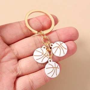 Vue détaillée de trois mini pendentifs de basket-ball sur un porte-clés en métal doré
