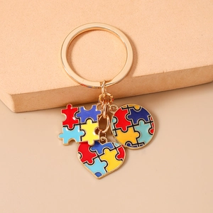 Dettaglio di un portachiavi dorato con ciondoli a cuore puzzle per l'autismo