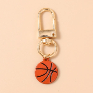 Close-up of golden metal lobster clasp and basketball pendant with orange enamel finish