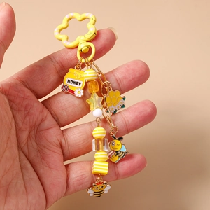 Détail du porte-clés abeille avec pendentif pot de miel et fermoir floral jaune vif