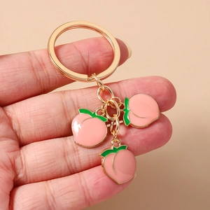 Detail of cute peach charms keychain with golden ring and pink enamel pendants