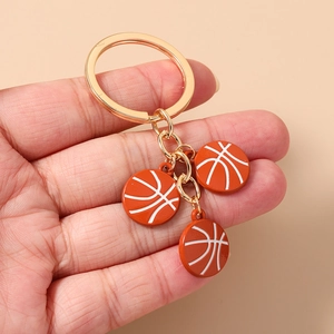 Détail de trois pendentifs de basket-ball orange sur un porte-clés en métal doré