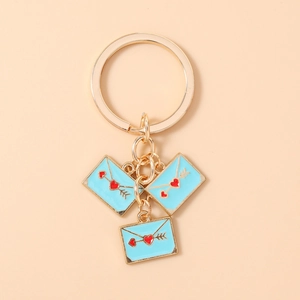 Close-up of three blue enamel heart envelope pendants on a gold keychain ring