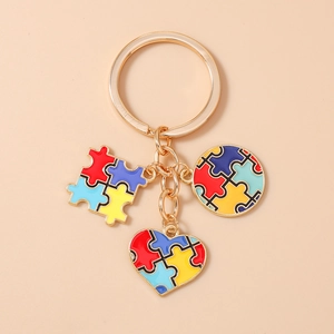 Dettaglio portachiavi autismo con ciondoli puzzle e cuore su anello in metallo oro