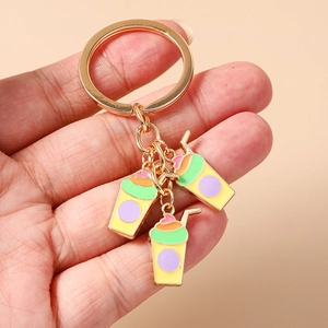 Close-up of golden keychain with three colorful milk tea charms held in hand