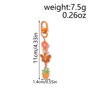Détails d'un porte-clés orange avec pendentifs en forme de cœur, papillon et cactus