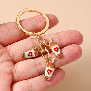 Detailed view of heart milk tea cup pendants on a gold keychain in pink and blue