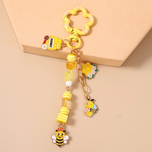 Détail d'un porte-clés abeille avec pot de miel, breloques de ruche et perles colorées