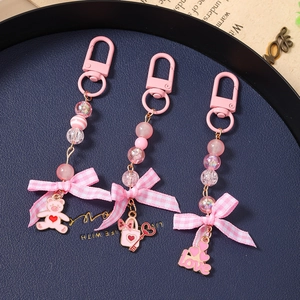 Pink beaded keychain set with fabric bow and heart bear charms on a navy tray