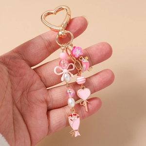 Detail of pink bird and flower keychain with heart clasp and beaded charms on hand
