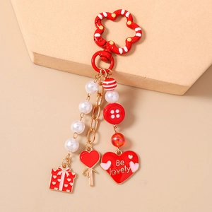 Detail of red flower clip keychain with faux pearls, heart charm and gift box pendant