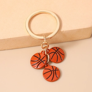 Détail d'un porte-clés en métal doré avec trois breloques de basket-ball orange vif