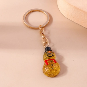 Macro detail of snowman keychain with golden glitter finish and festive scarf decoration
