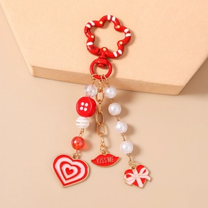 Detail of beaded keychain with Kiss Me red lips, heart pendants and white pearls charms