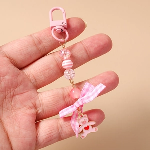 Close-up of pink beaded keychain with a cute bear charm and pink checkered ribbon bow