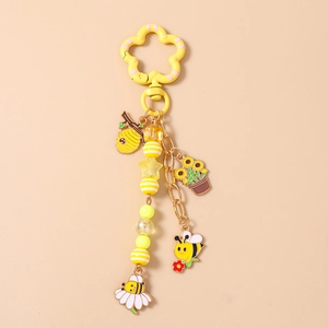 Détail du porte-clés abeille avec fermoir fleur jaune et breloques en émail sur chaîne