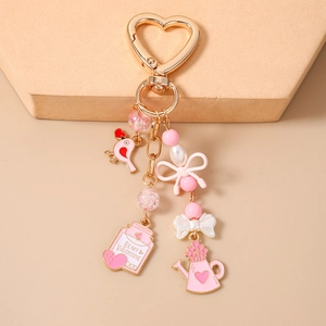 Detailed view of beaded bird and 'Be My Valentine' jar charms on a pink heart keychain