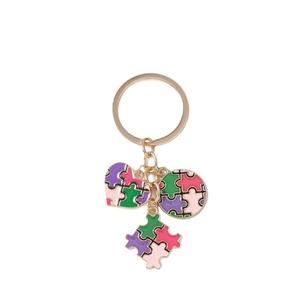 Portachiavi a cuore con puzzle placcato oro e ciondoli in smalto colorato su sfondo bianco