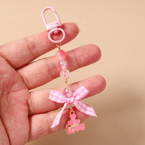 Close-up of pink beaded keychain with fabric bow and love heart enamel pendant