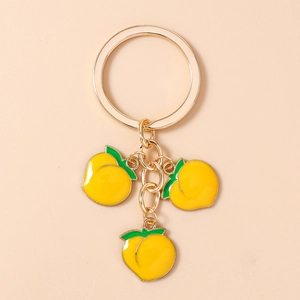 Close-up of golden keychain featuring three yellow peach pendants with green leaves